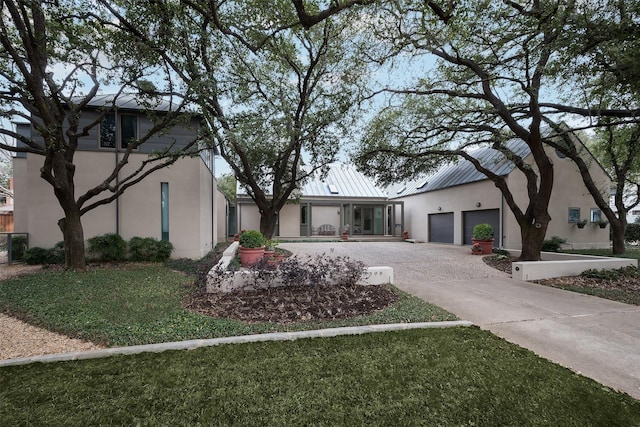 view of front facade with driveway, metal roof, and stucco siding