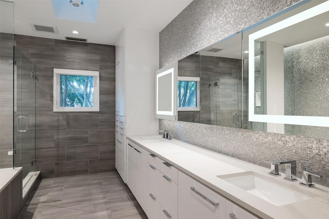 bathroom with tasteful backsplash, a stall shower, a sink, and a healthy amount of sunlight