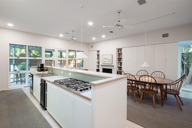 kitchen featuring stainless steel gas stovetop, white cabinets, a fireplace, and a sink