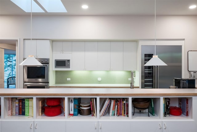 kitchen featuring a skylight, tasteful backsplash, appliances with stainless steel finishes, white cabinetry, and recessed lighting