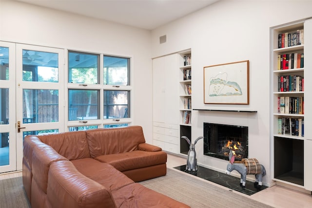 living area featuring a fireplace with flush hearth and built in features