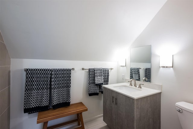 bathroom with toilet, vaulted ceiling, and vanity