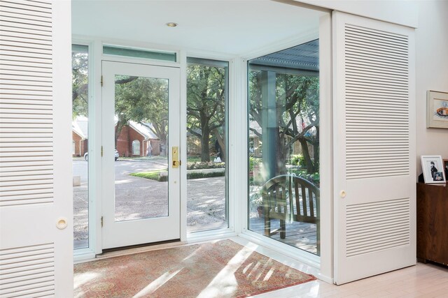 doorway to outside with a wall of windows and wood finished floors