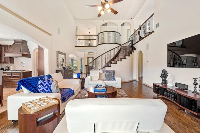 living area featuring visible vents, arched walkways, ceiling fan, stairway, and wood finished floors