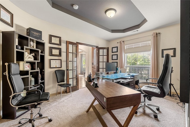 carpeted office space with french doors, a tray ceiling, visible vents, and baseboards