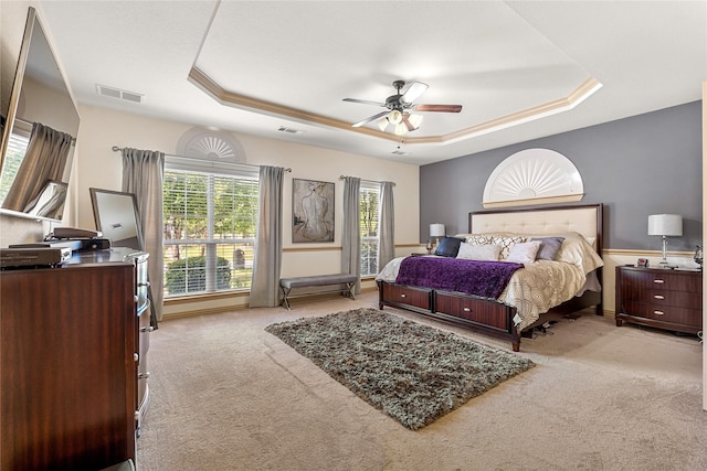 bedroom with light colored carpet, a tray ceiling, and visible vents