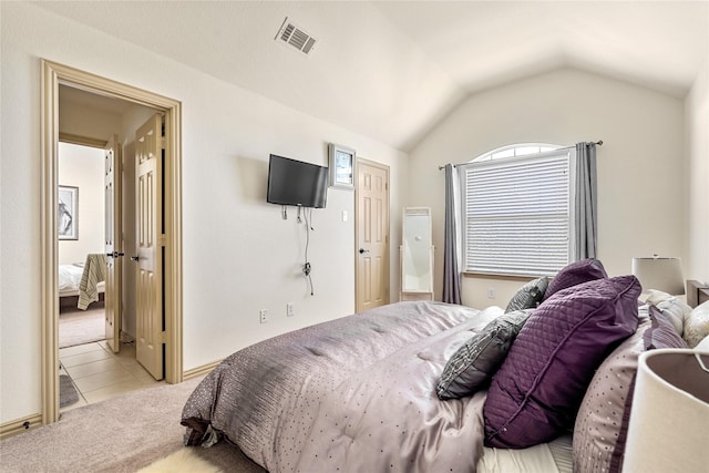 bedroom featuring light colored carpet, visible vents, vaulted ceiling, and light tile patterned floors