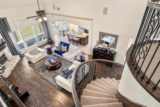 living room with stairs, high vaulted ceiling, wood finished floors, and arched walkways