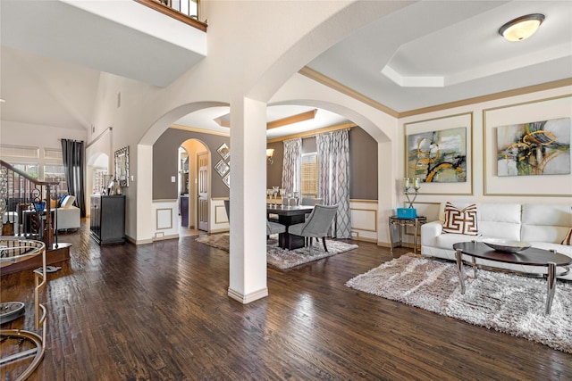 foyer with stairs, a tray ceiling, arched walkways, and wood finished floors