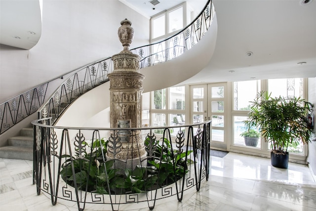 staircase featuring marble finish floor and a high ceiling