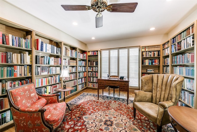 living area featuring ceiling fan, bookshelves, wood finished floors, and recessed lighting