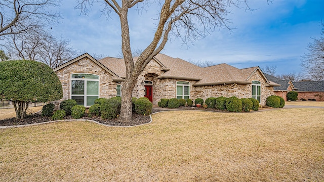 french country style house featuring roof with shingles, brick siding, and a front lawn