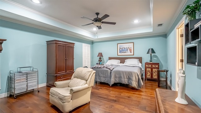 bedroom featuring baseboards, visible vents, a raised ceiling, ornamental molding, and wood finished floors