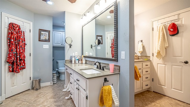 full bath with toilet, a ceiling fan, vanity, baseboards, and tile patterned floors