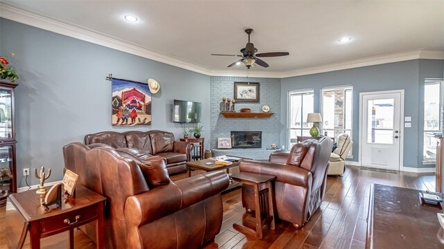 living area with a brick fireplace, baseboards, dark wood finished floors, and crown molding