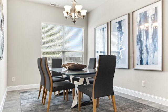 dining space featuring dark wood-style floors, visible vents, baseboards, and an inviting chandelier