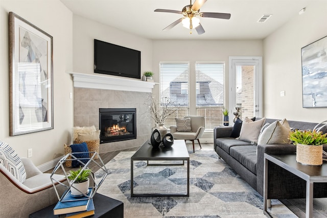 living area with visible vents, a fireplace, baseboards, and ceiling fan