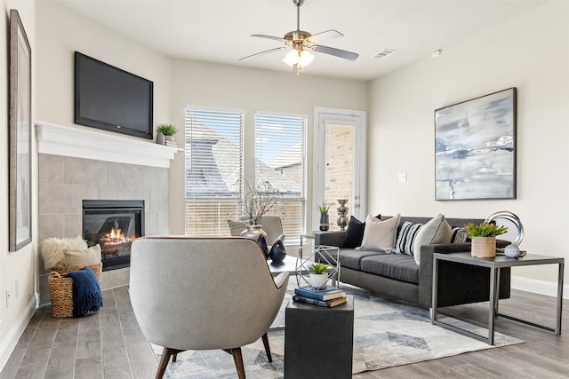 living area with baseboards, a fireplace, visible vents, and wood finished floors