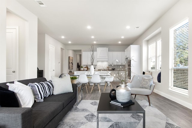 living area featuring light wood-type flooring, baseboards, visible vents, and recessed lighting