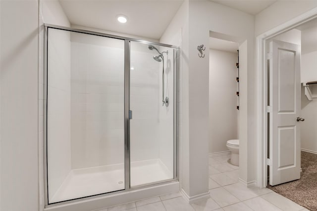 full bathroom featuring toilet, a stall shower, baseboards, and tile patterned floors