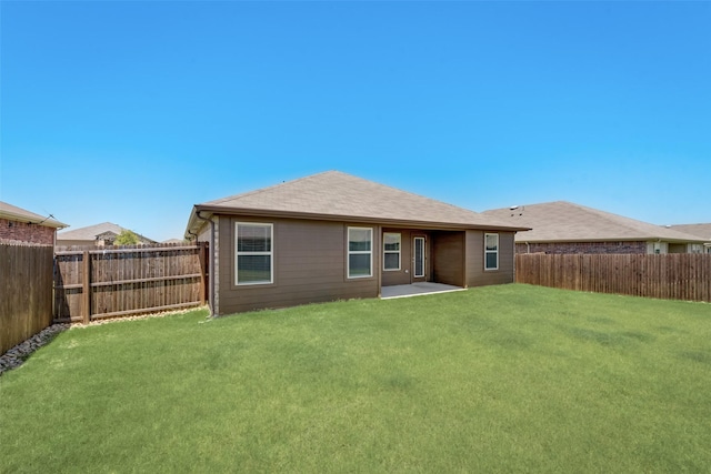 rear view of house featuring a yard and a fenced backyard