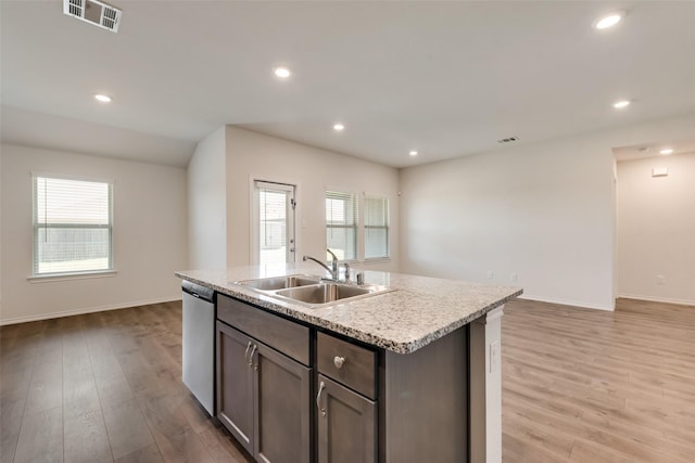 kitchen with a wealth of natural light, a sink, light wood finished floors, and stainless steel dishwasher