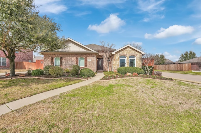 ranch-style home featuring a front yard, stone siding, brick siding, and fence