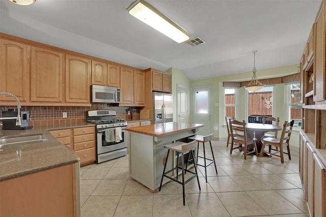 kitchen featuring stainless steel appliances, a sink, visible vents, vaulted ceiling, and tasteful backsplash