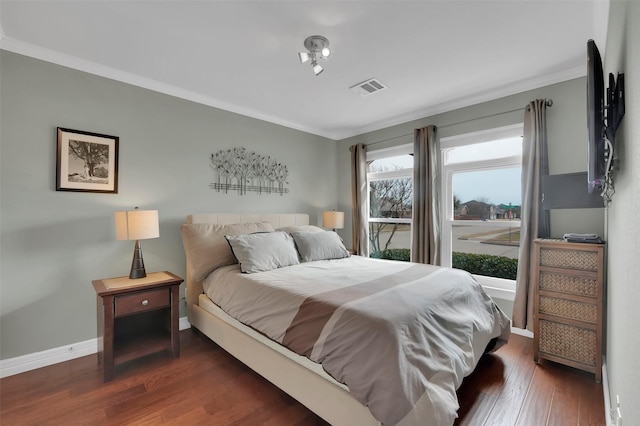 bedroom with baseboards, crown molding, visible vents, and wood finished floors