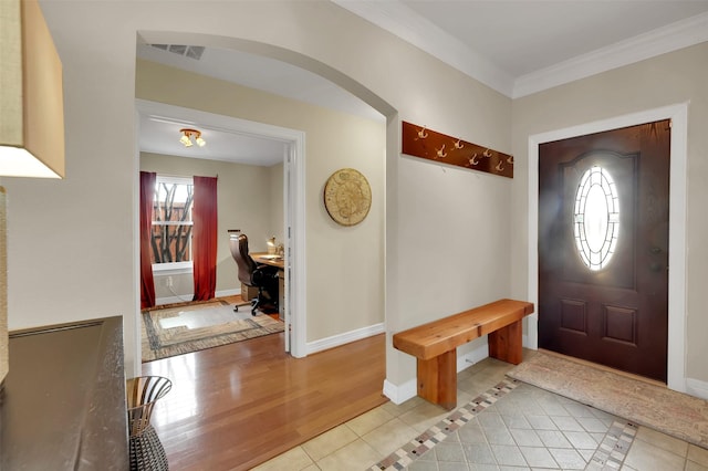 mudroom featuring light tile patterned floors, baseboards, visible vents, arched walkways, and crown molding