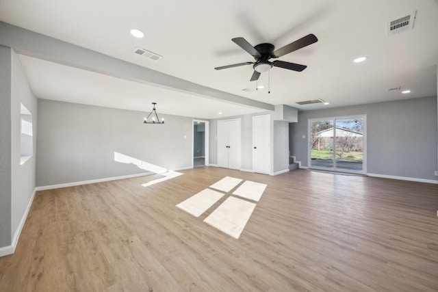 unfurnished living room featuring visible vents, baseboards, and wood finished floors