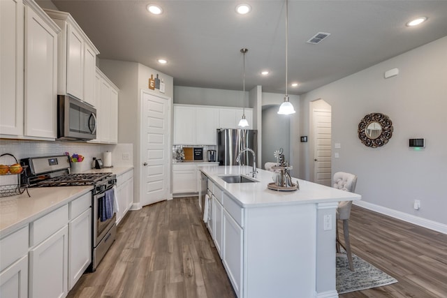 kitchen featuring wood finished floors, appliances with stainless steel finishes, backsplash, and a sink