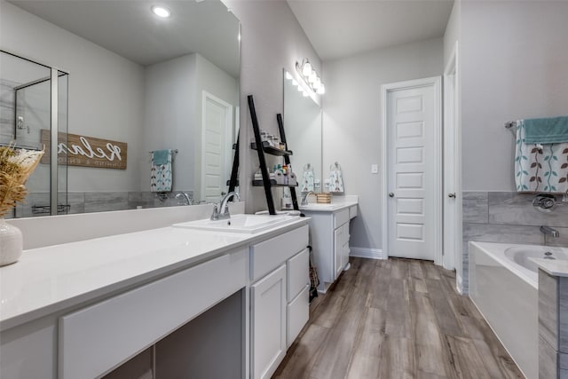 full bath featuring a garden tub, recessed lighting, wood finished floors, vanity, and a stall shower