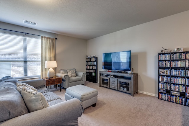 living room featuring light carpet, visible vents, baseboards, and a textured ceiling