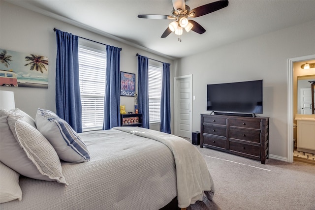 carpeted bedroom with ensuite bath, baseboards, and ceiling fan