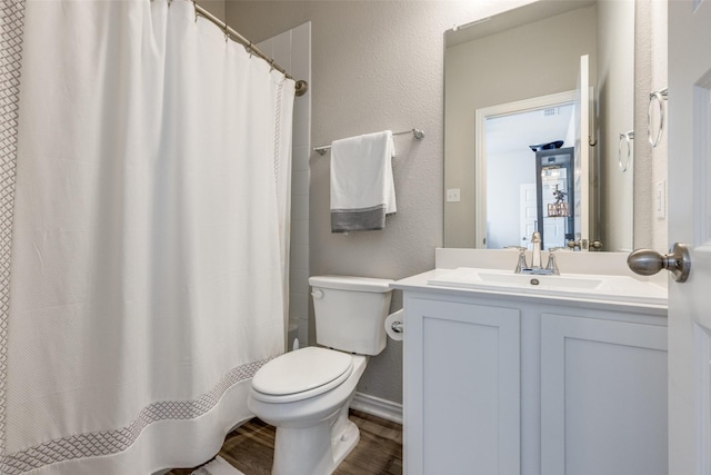 bathroom with a textured wall, toilet, a shower with shower curtain, wood finished floors, and vanity