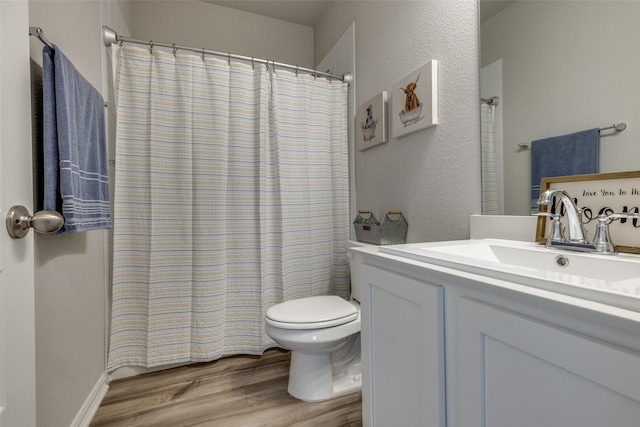 full bathroom featuring a textured wall, toilet, wood finished floors, vanity, and a shower with curtain