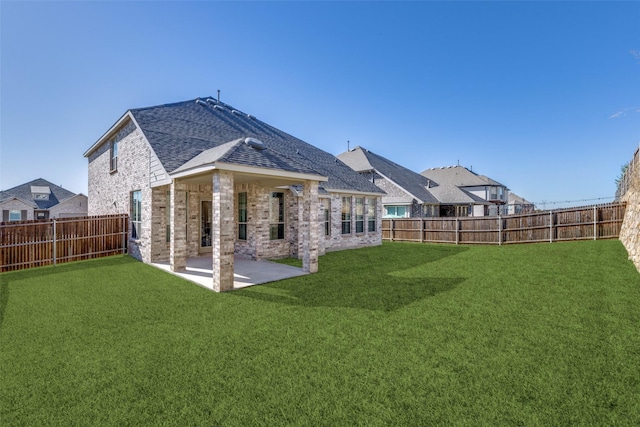 rear view of house featuring a patio, brick siding, a lawn, and a fenced backyard