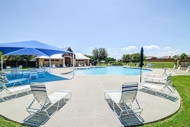 community pool with a patio area and fence