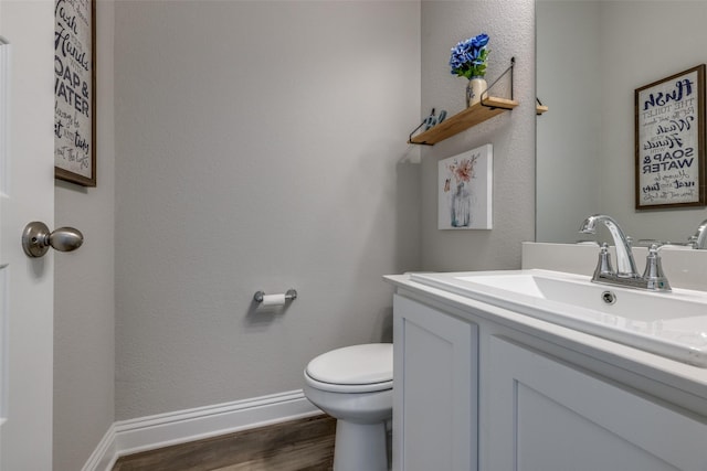 bathroom with toilet, baseboards, wood finished floors, and vanity