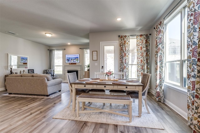 dining space featuring light wood-style floors, baseboards, a fireplace, and visible vents