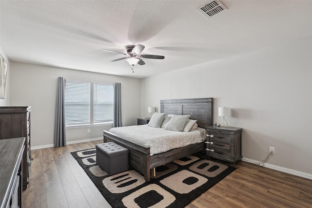 bedroom featuring a textured ceiling, wood finished floors, visible vents, and baseboards