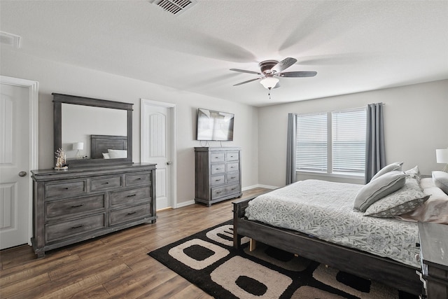 bedroom featuring visible vents, dark wood finished floors, baseboards, and ceiling fan