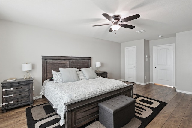 bedroom featuring dark wood-style floors, a ceiling fan, visible vents, and baseboards