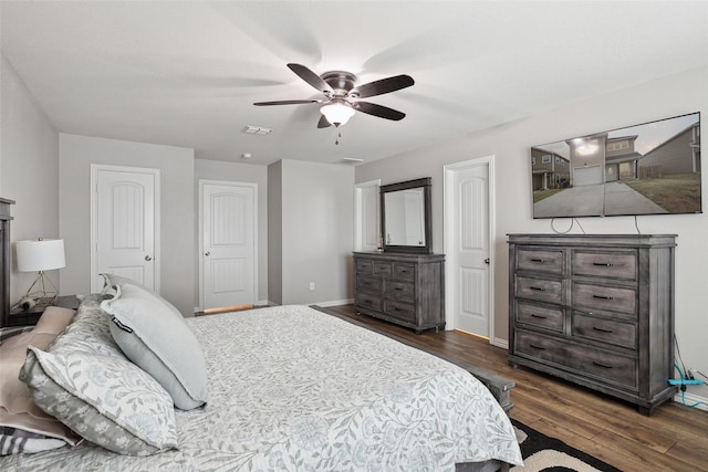 bedroom featuring a ceiling fan, dark wood-style flooring, visible vents, and baseboards