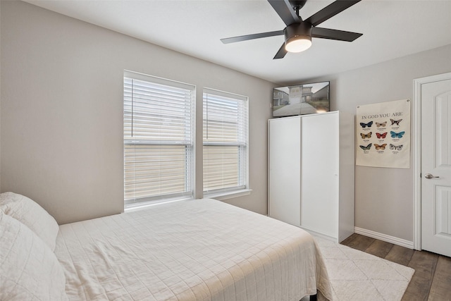 bedroom with ceiling fan, wood finished floors, and baseboards