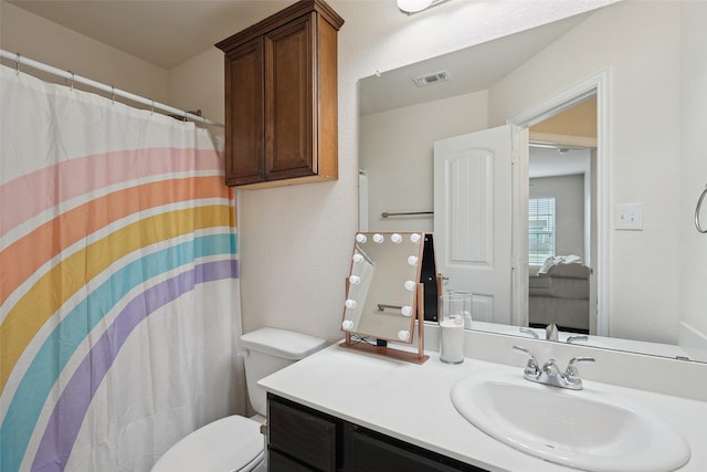 bathroom featuring toilet, curtained shower, visible vents, and vanity