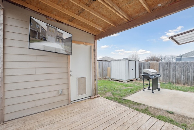 wooden deck with an outbuilding, a storage unit, area for grilling, and fence