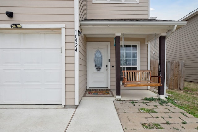 view of exterior entry with a garage and fence