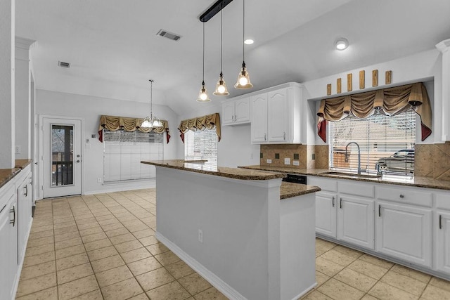 kitchen with visible vents, decorative backsplash, dark stone counters, white cabinetry, and a sink